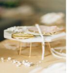 Nahaufnahme von weißen Perlen und goldenem Werkzeug auf hellem Tisch – Schmuckmaterial für handgefertigten Schmuck