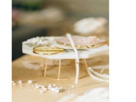 Nahaufnahme von weißen Perlen und goldenem Werkzeug auf hellem Tisch – Schmuckmaterial für handgefertigten Schmuck