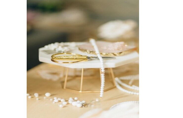 Nahaufnahme von weißen Perlen und goldenem Werkzeug auf hellem Tisch – Schmuckmaterial für handgefertigten Schmuck