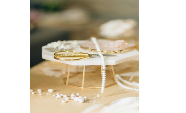 Nahaufnahme von weißen Perlen und goldenem Werkzeug auf hellem Tisch – Schmuckmaterial für handgefertigten Schmuck