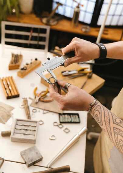 Schmuckdesigner misst Metallring in Werkstatt – präzise Arbeit mit professionellen Werkzeugen